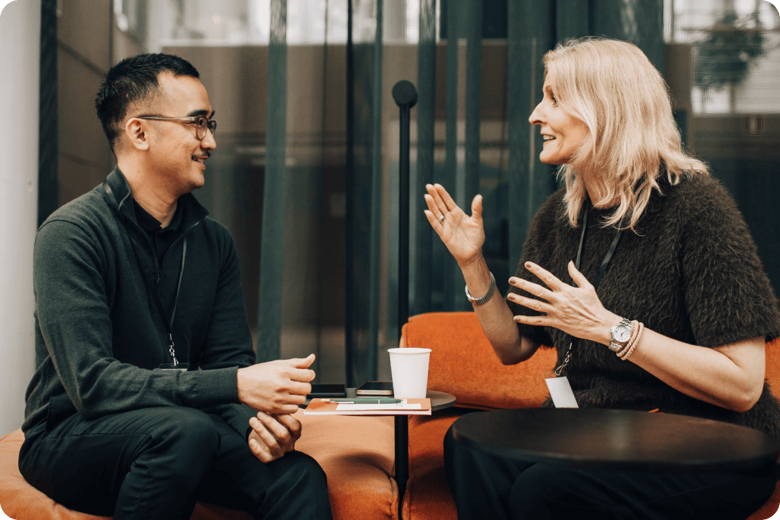 Two coworkers having an animated conversation in a lounge area.