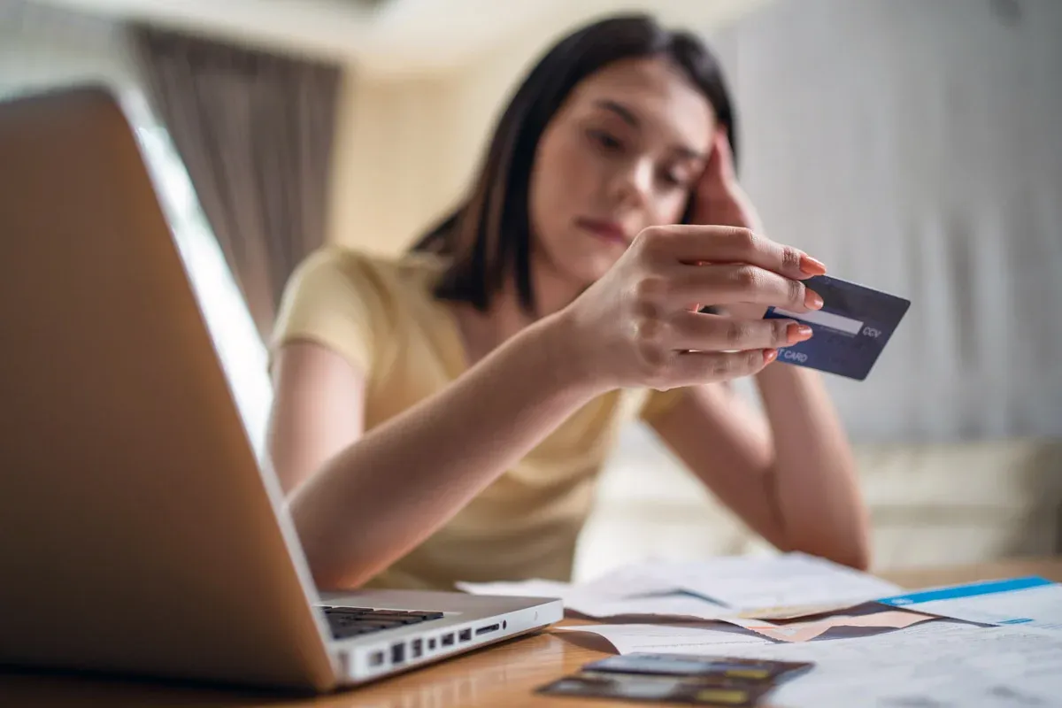 a woman looking at a credit card with regret