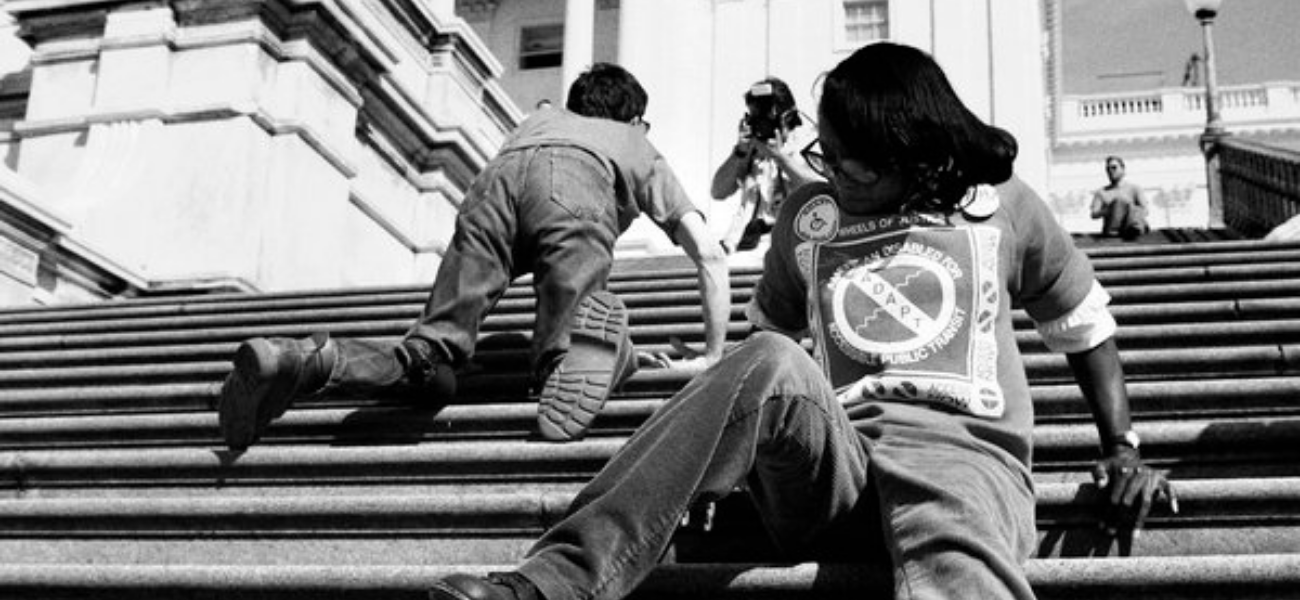 Black and white photograph of protesters climbing up the steps to the U.S. Capitol Building on their hands and knees.