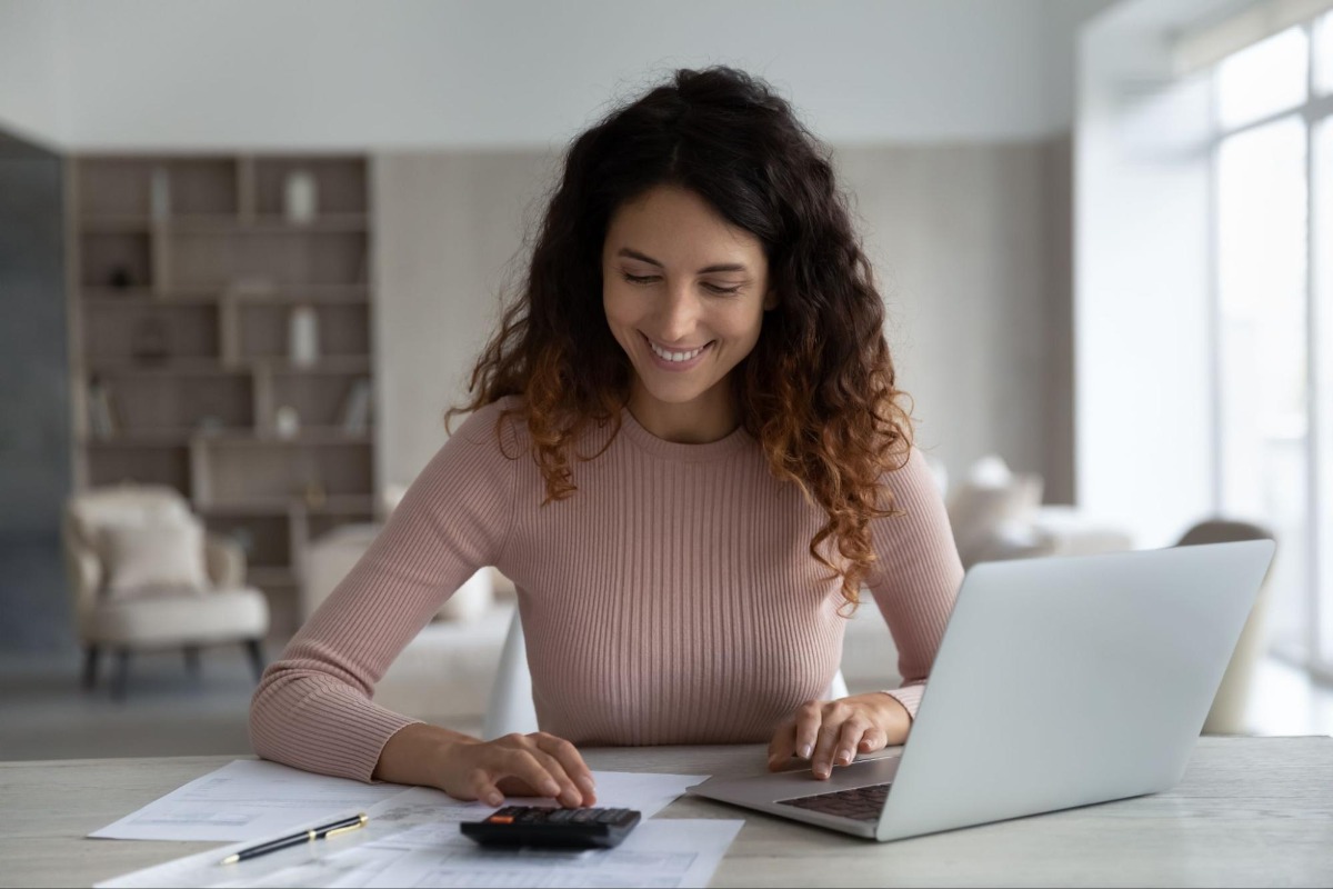 Woman with a calculator in front of a laptop