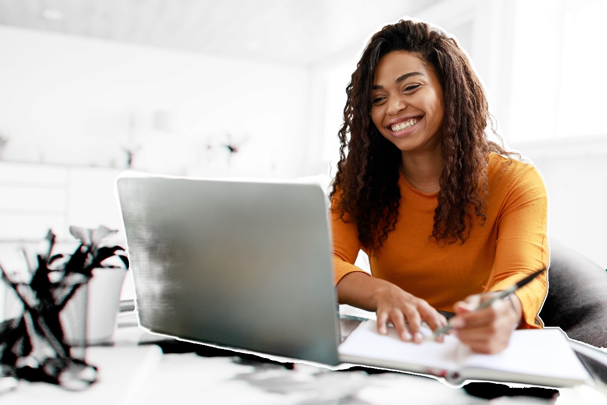 Happy woman sitting at a laptop writing