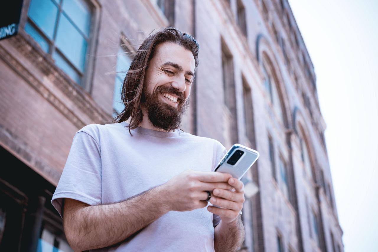 Man smiling while looking at his phone