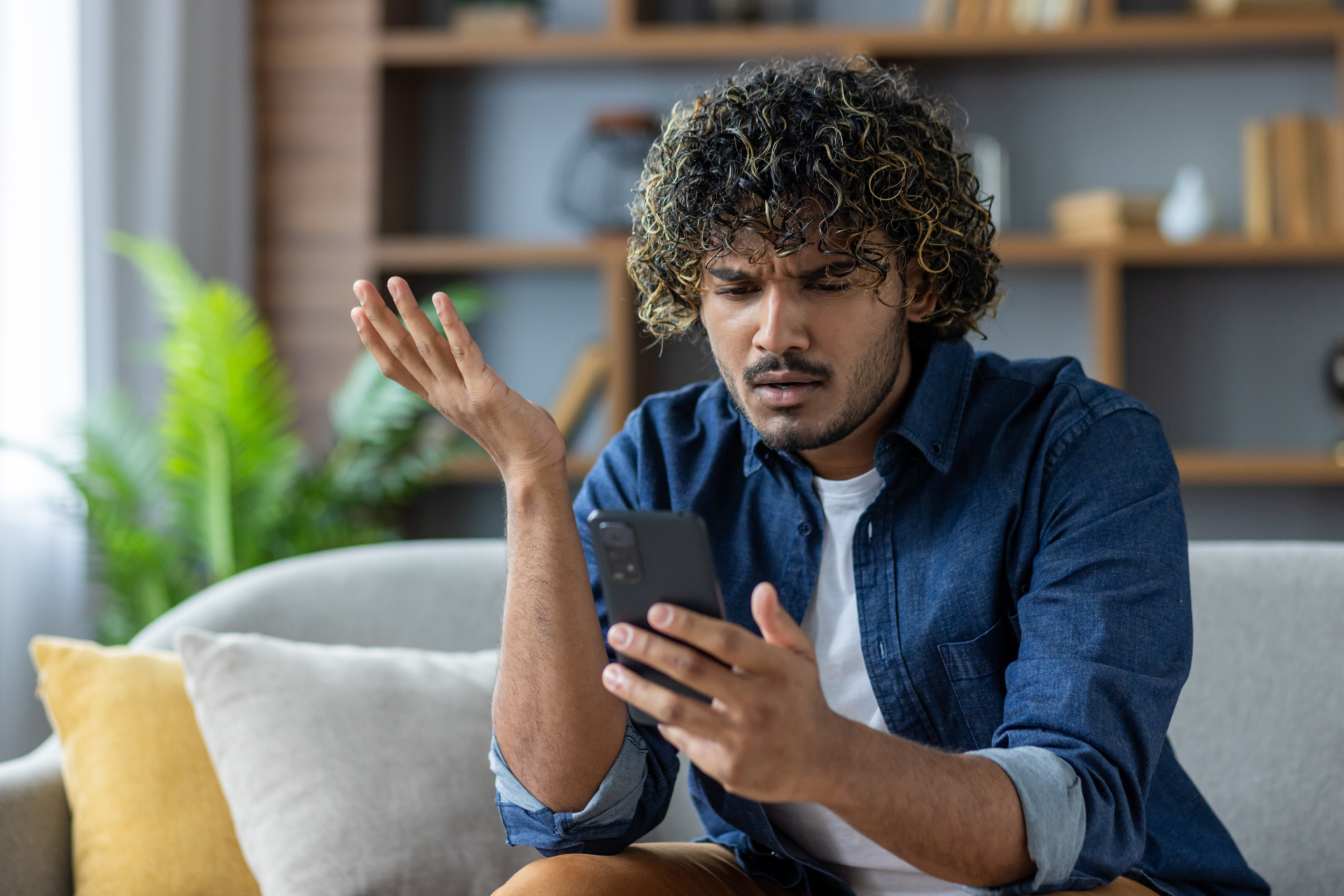 Man sitting on a couch looking pissedly at his phone