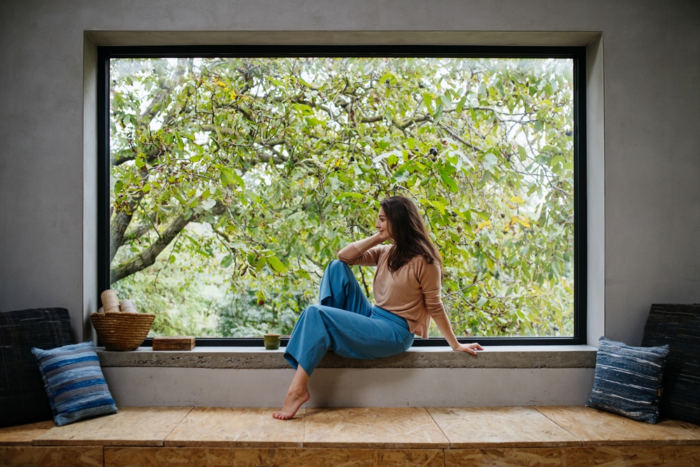 Woman sitting down relaxing under enormous bay window