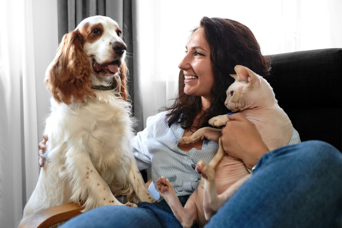 A woman smiling holding a cat and a dog