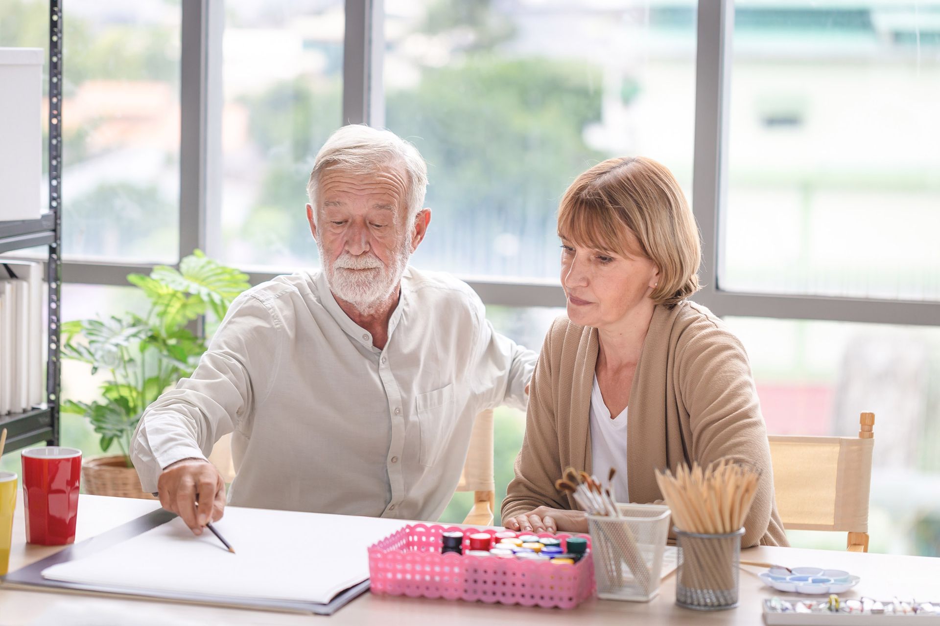 A retiree couple writing at their kitchen table