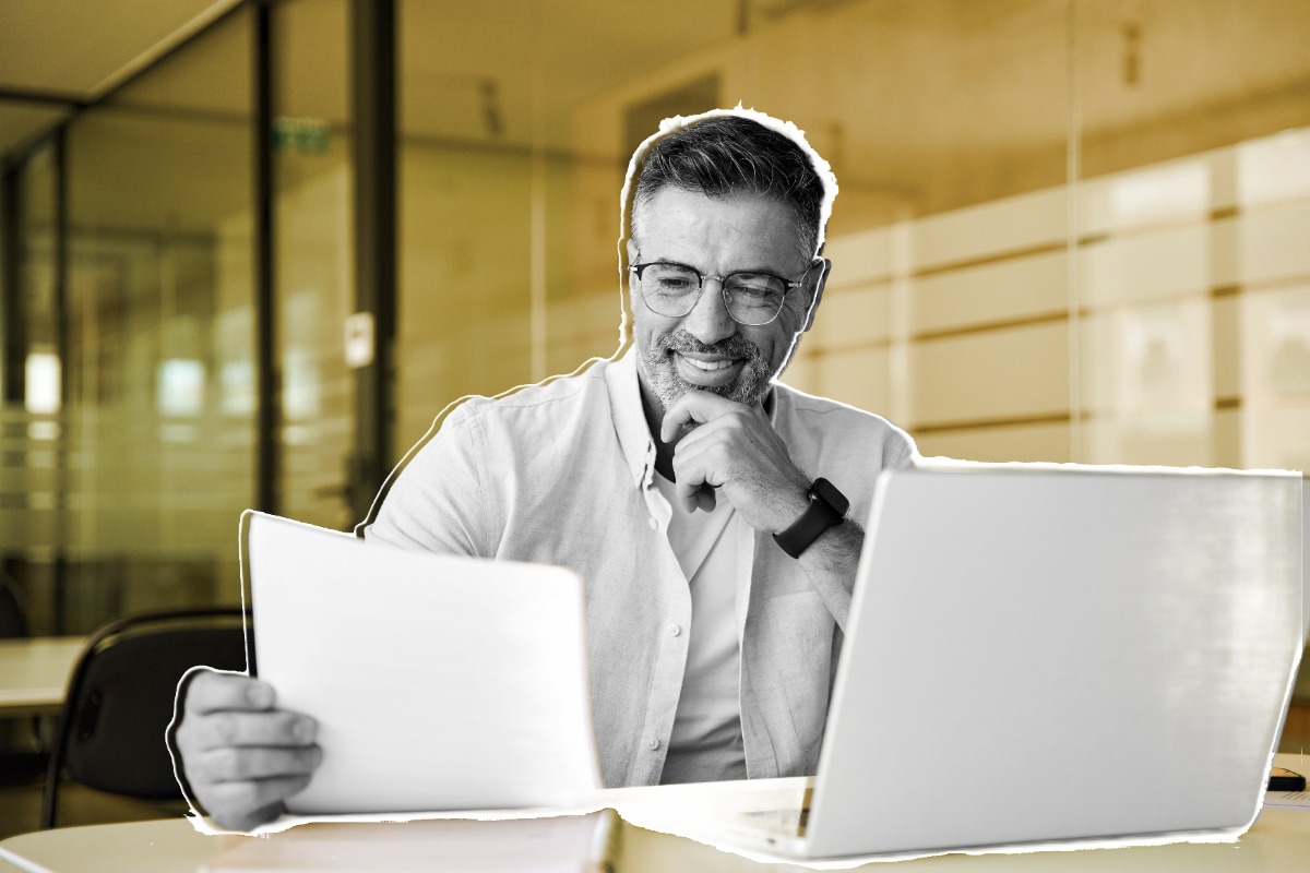 Man sitting at a desk smiling and looking at a document