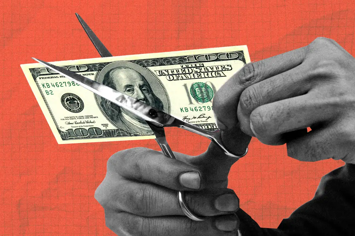 hands cutting $100 bill