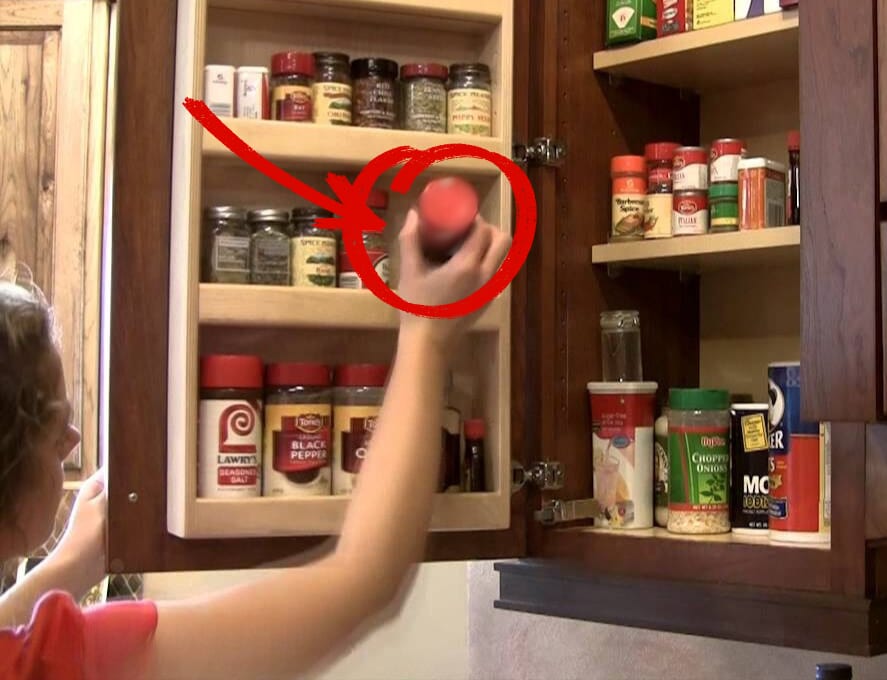 Woman reaching for spice jar in cabinet