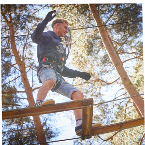 A man balances his way over a Go Ape high ropes crossing