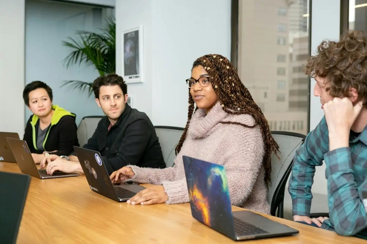 4 people sitting at a table with laptops