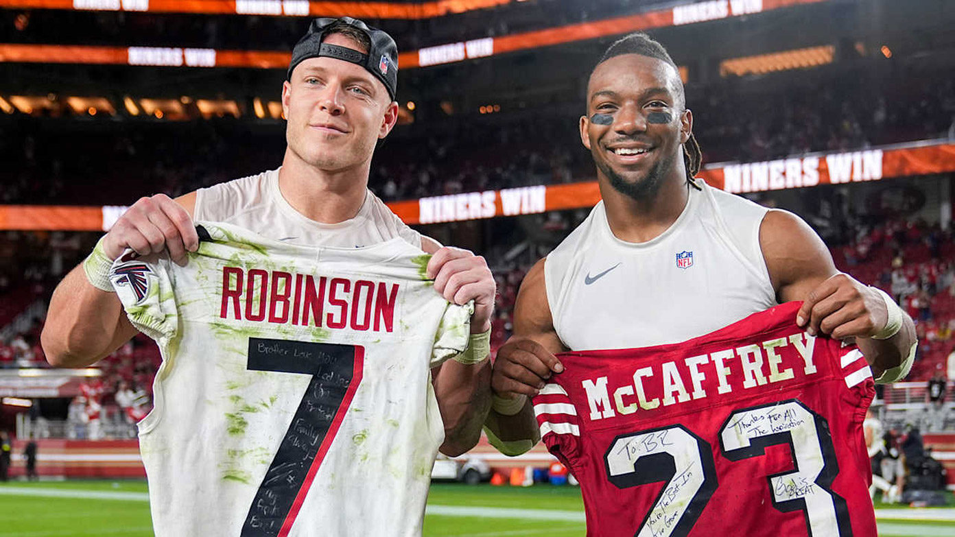 Bijan Robinson and Christian McCaffrey holding jerseys