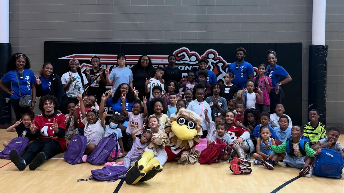 Mike Ford Jr. with YMCA staff, youth, and Freddie Falcon.