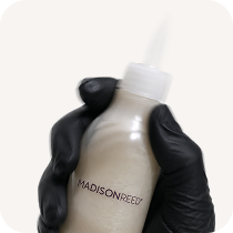 hand wearing black glove holding Madison Reed product