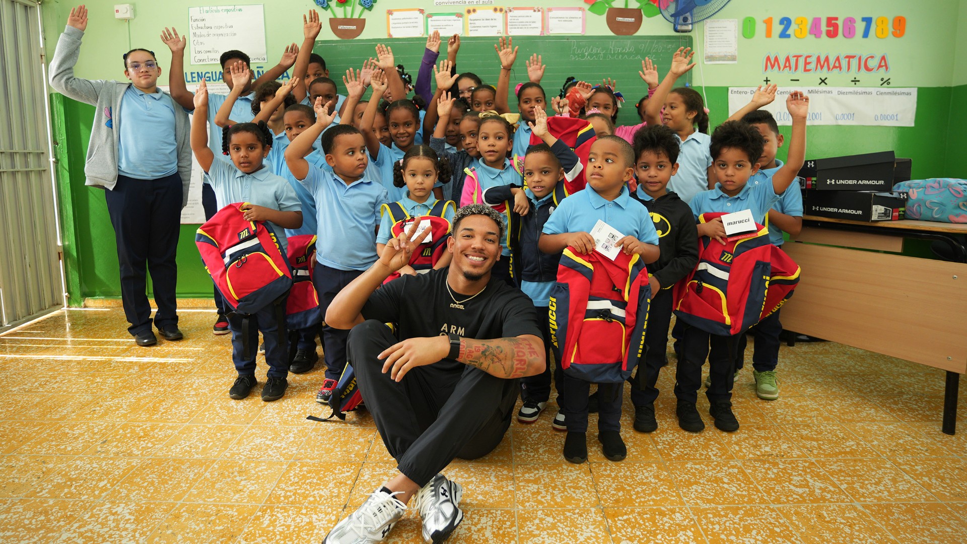 Angel Genao poses with students at Felicia Ortega Frías Elementary School